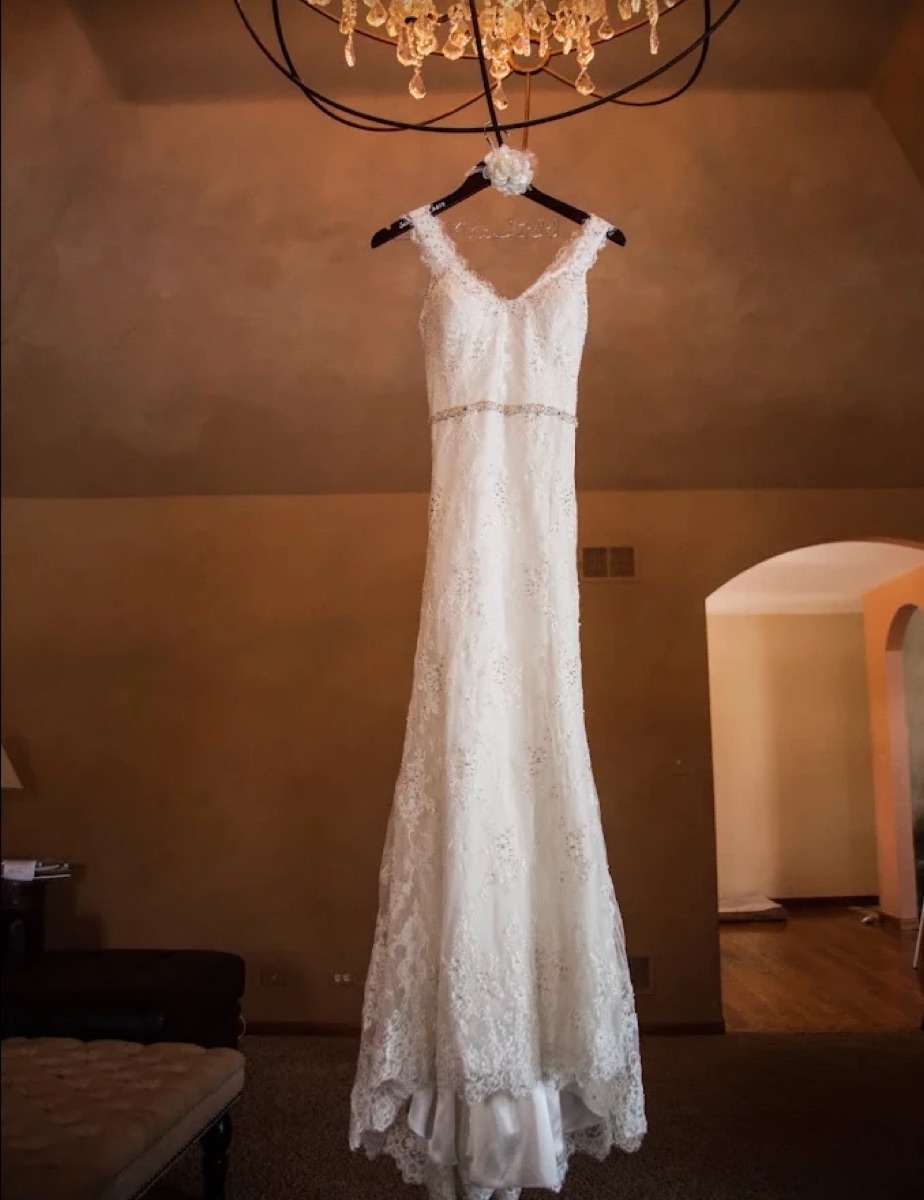 Altered wedding gown hanging beneath a chandelier