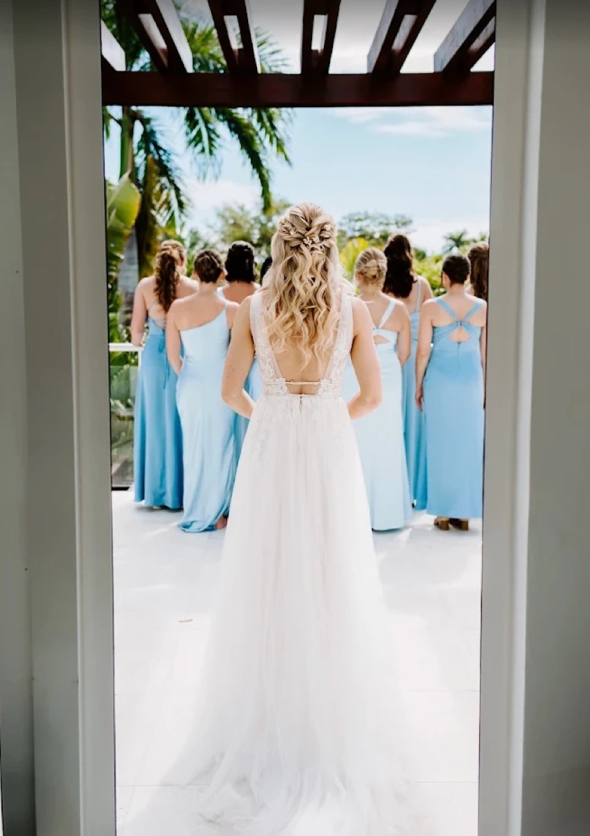 Bride facing her bridesmaids in blue dresses